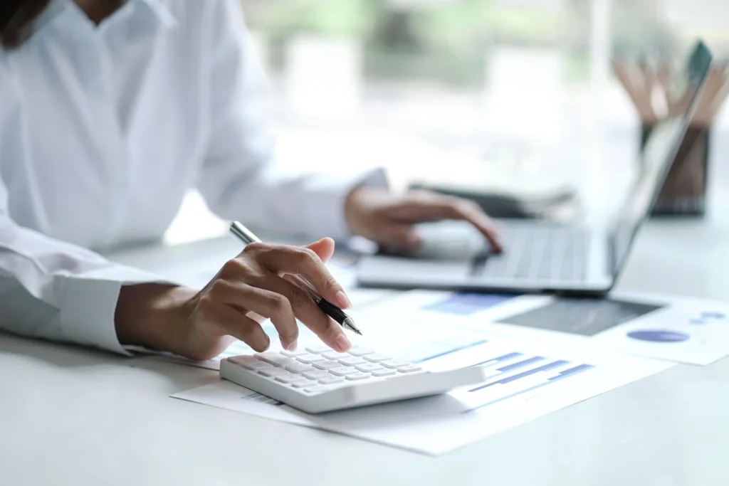 Cropped view of a bookkeeper's hands using a calculator on a clear desk in an office.